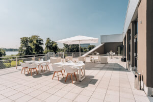 Sonnenterrasse der Veranstaltungsebene mit Loungmöbeln und Sonnenschirm.