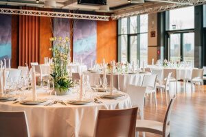 Großer Veranstaltungsraum mit eingedeckten runden Tischen